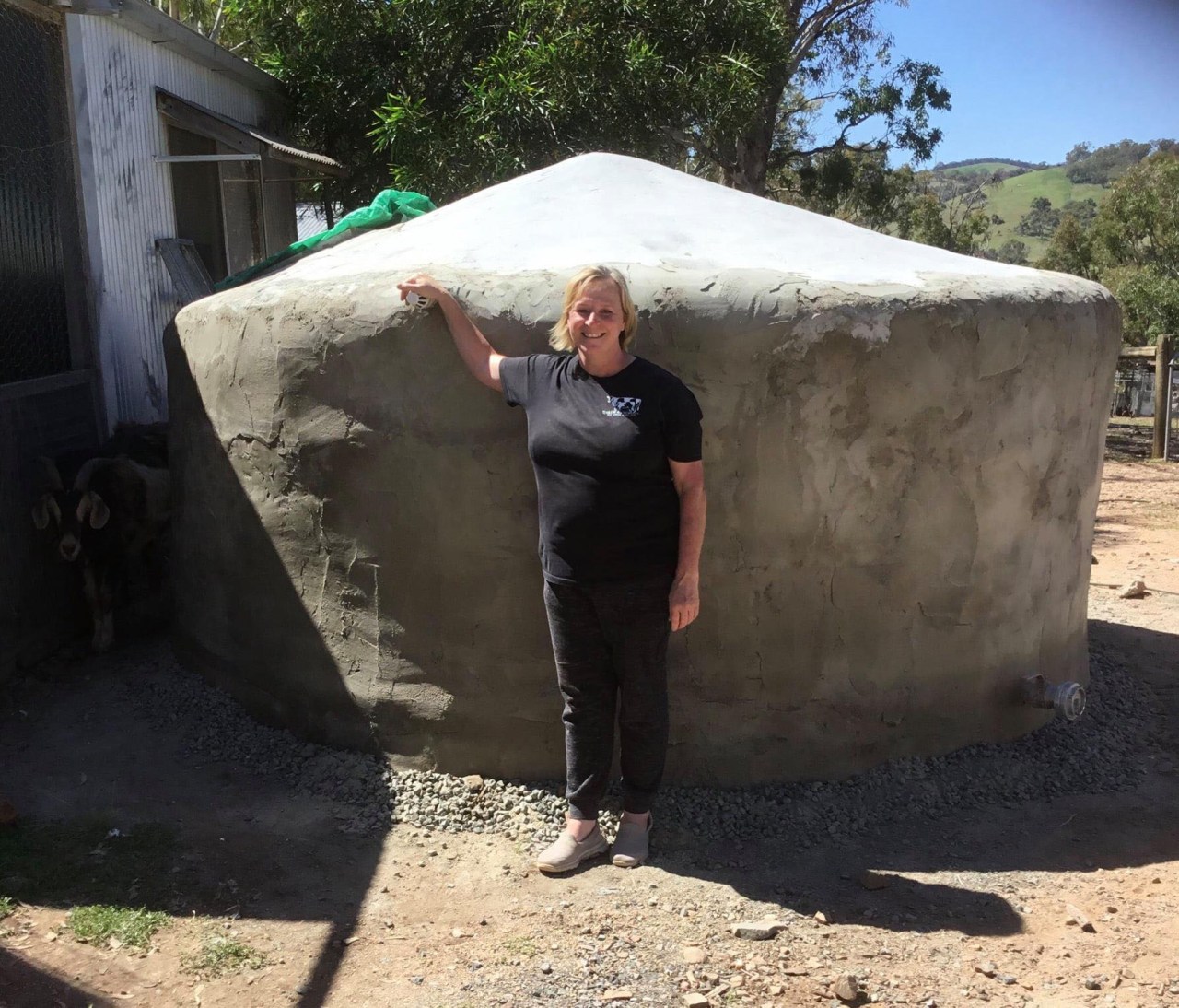 Kerrie Carroll standing in front of the completed earthbag tank