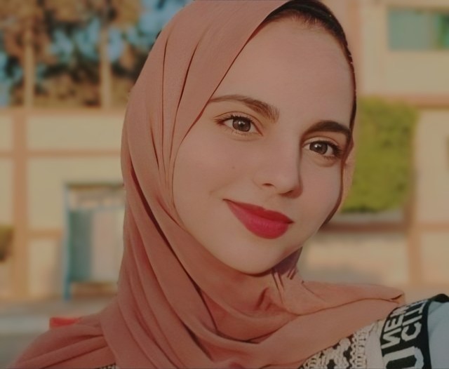 A head shot of Dina Turkeya. She is smiling and wearing a head scarf.